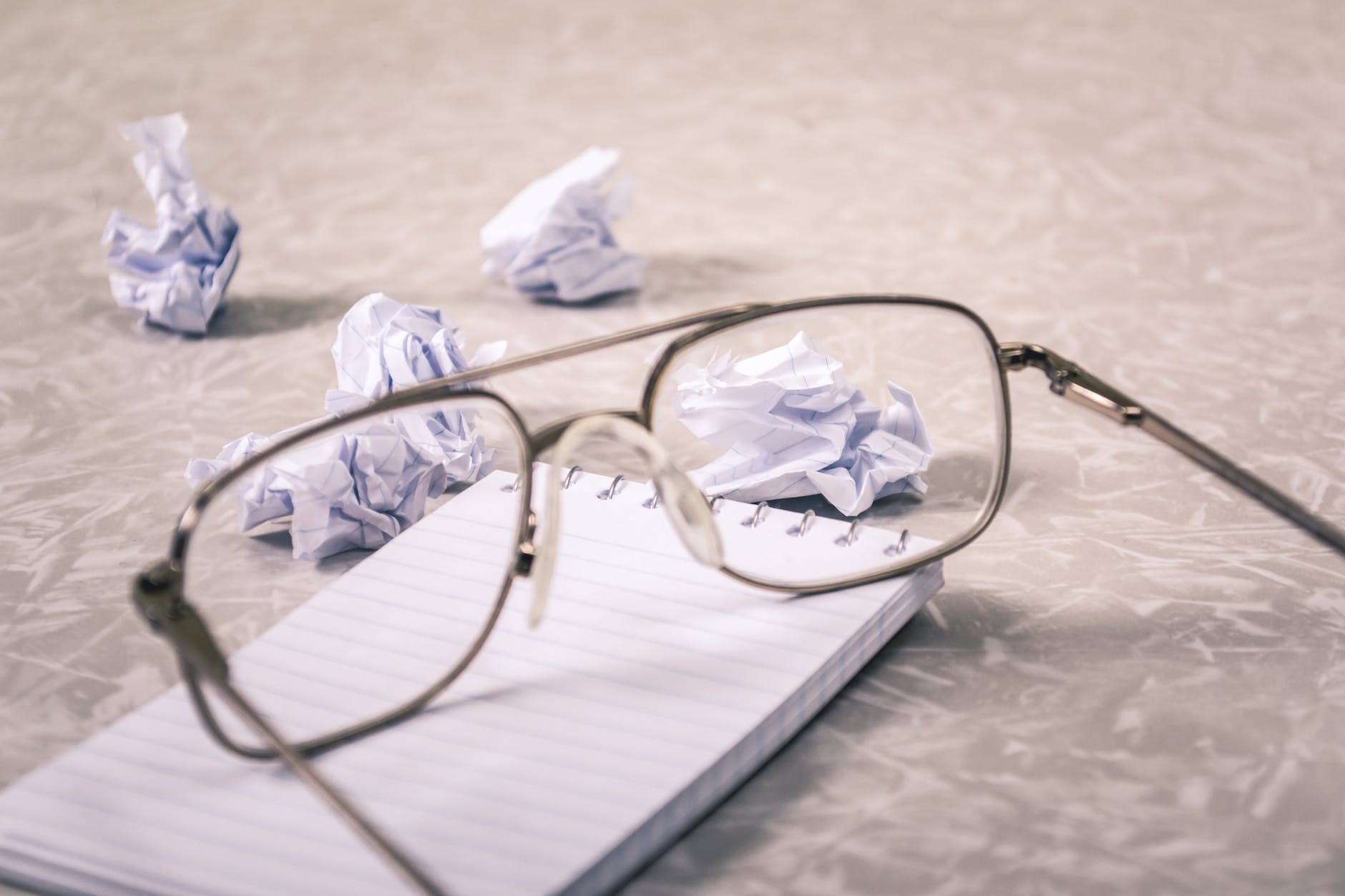 close up photography of eyeglasses near crumpled papers